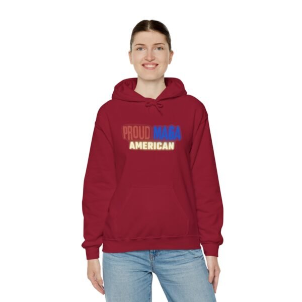 Smiling woman wearing a red "Proud MAGA American" hoodie with bold patriotic lettering in red, white, and blue. A perfect mix of comfort and conservative pride.